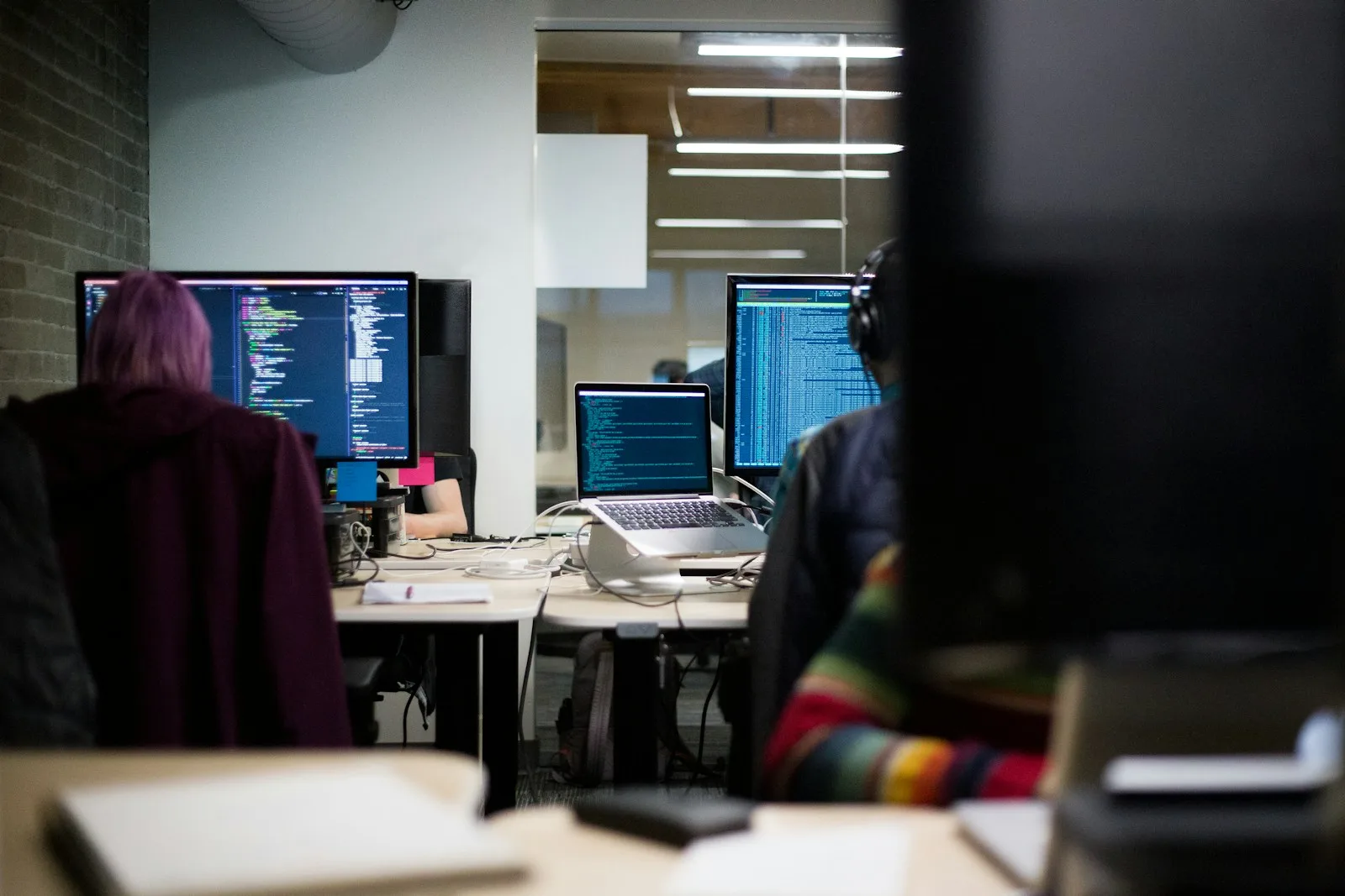 Sviluppatori al lavoro su un sito custom, monitor con codice in un ufficio